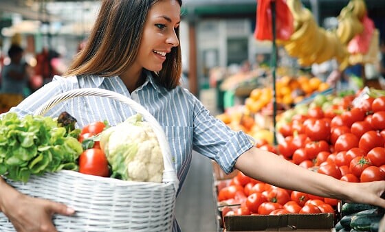 Frau beim Einkauf von frischem Gem&uuml;se auf einem veganen Markt.
