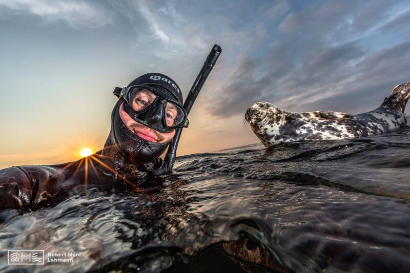 Robert Marc Lehmann in Taucherausrüstung unter Wasser mit einer Robbe