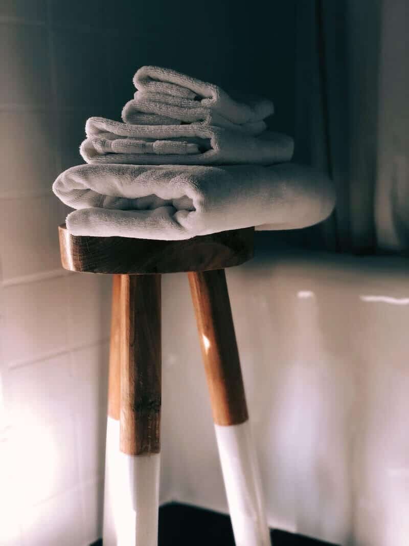Saubere, gefaltete Handt&uuml;cher auf einem Holz-Hocker, ideal f&uuml;r Spa oder Badezimmer.