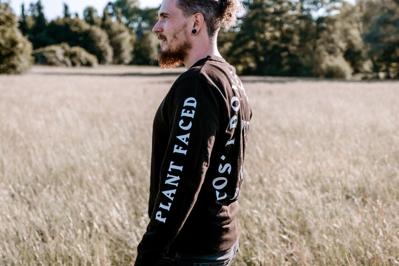 Person von der Seite mit Plant-Faced-Schriftzug auf dem Ärmel in einem Feld