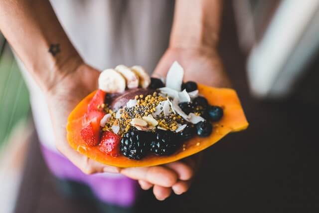 Vegan fruit taco with berries, bananas and nuts, served in a paper bag.
