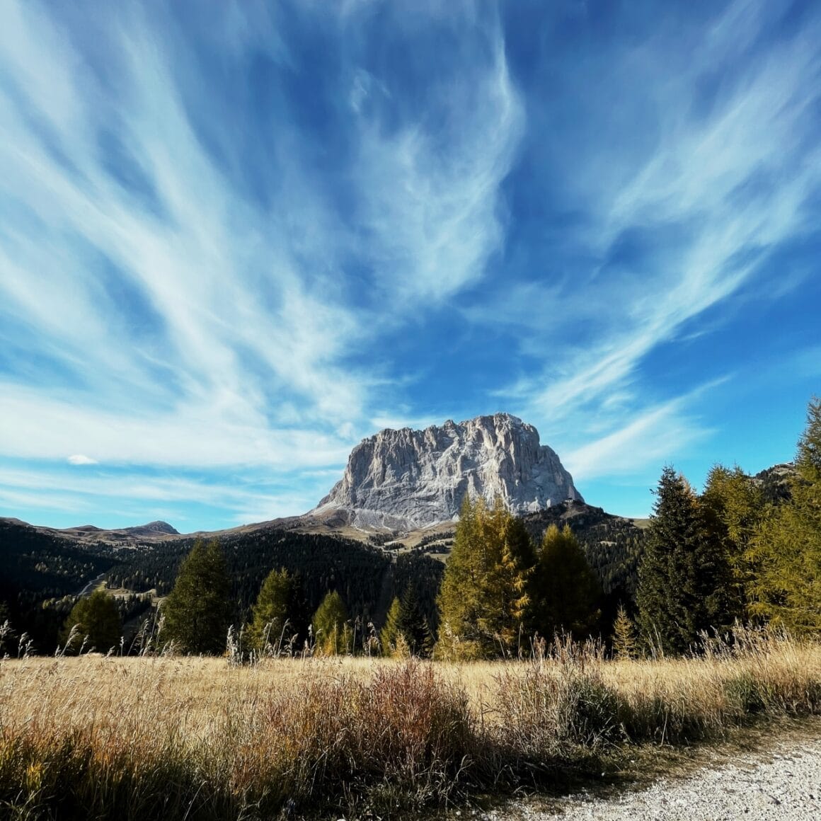 Berglandschaft unter blauem Himmel mit Wolken, umgeben von W&auml;ldern und Wiesen. Perfekt f&uuml;r Natur- un.