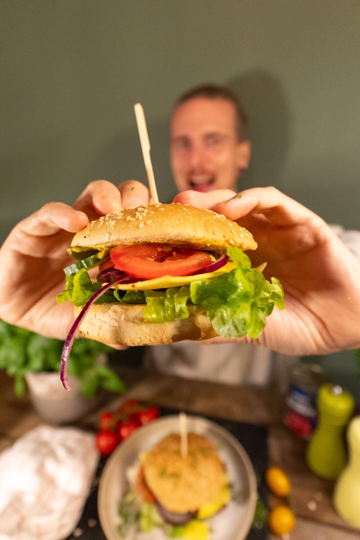 Yannick hat einen Burger in der Hand und schaut Ihn mit offenem Mund an