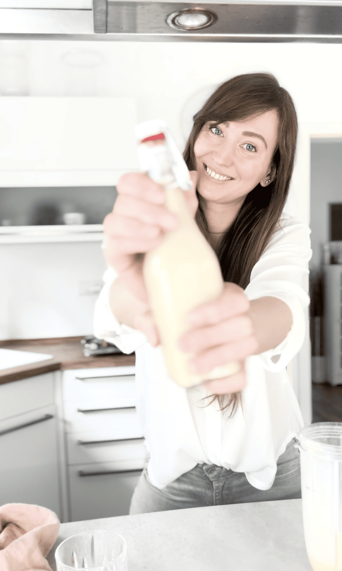 Ana hebt selbstgemachten veganen Eierlikör in einer Glasflasche hoch