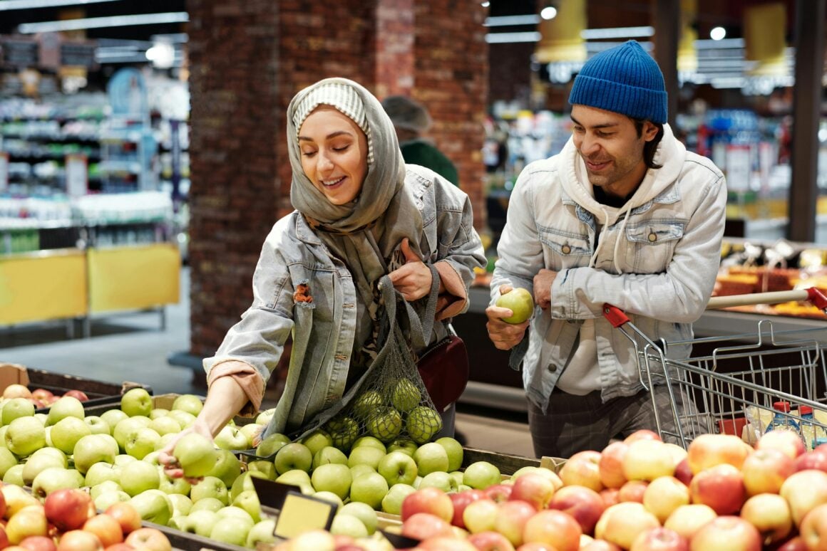 Junges Paar kauft nachhaltige, regionale Äpfel im Supermarkt – Fokus auf bewusster, pflanzlicher Ernährung