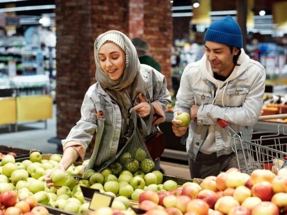 Junges Paar kauft nachhaltige, regionale Äpfel im Supermarkt – Fokus auf bewusster, pflanzlicher Ernährung