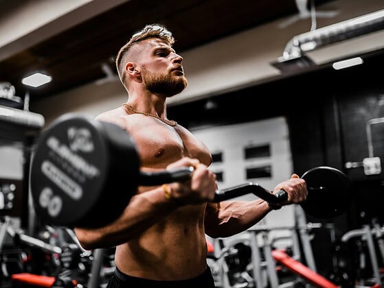 Mann beim Krafttraining mit Hantel im Fitnessstudio.