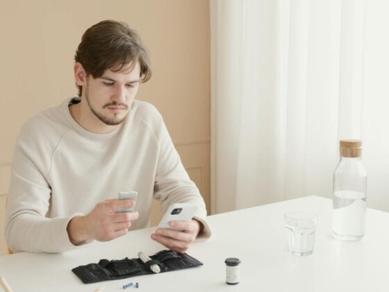 Mann testet Gesundheitswerte mit Selbsttest-Kit und Smartphone am Tisch