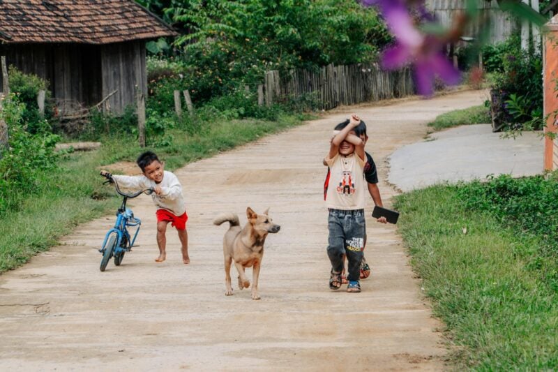 Ein Gruppe kleiner Kinder läuft mit ihrem Hund durch das Dorf