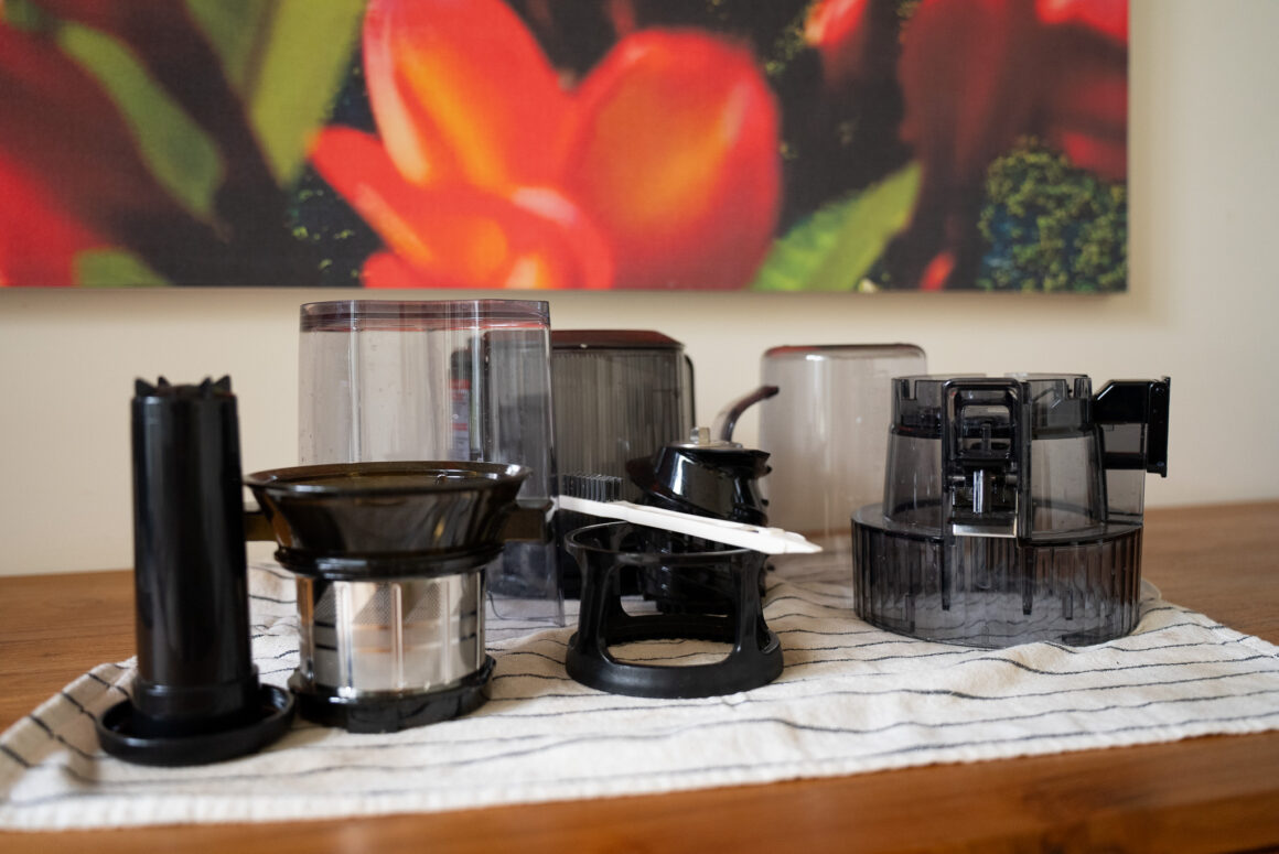 Zerlegte Hurom H70-ST Teile auf Küchentuch – Sieb, Presskammer und Bürste für schnelle, einfache Reinigung nach dem Entsaften.