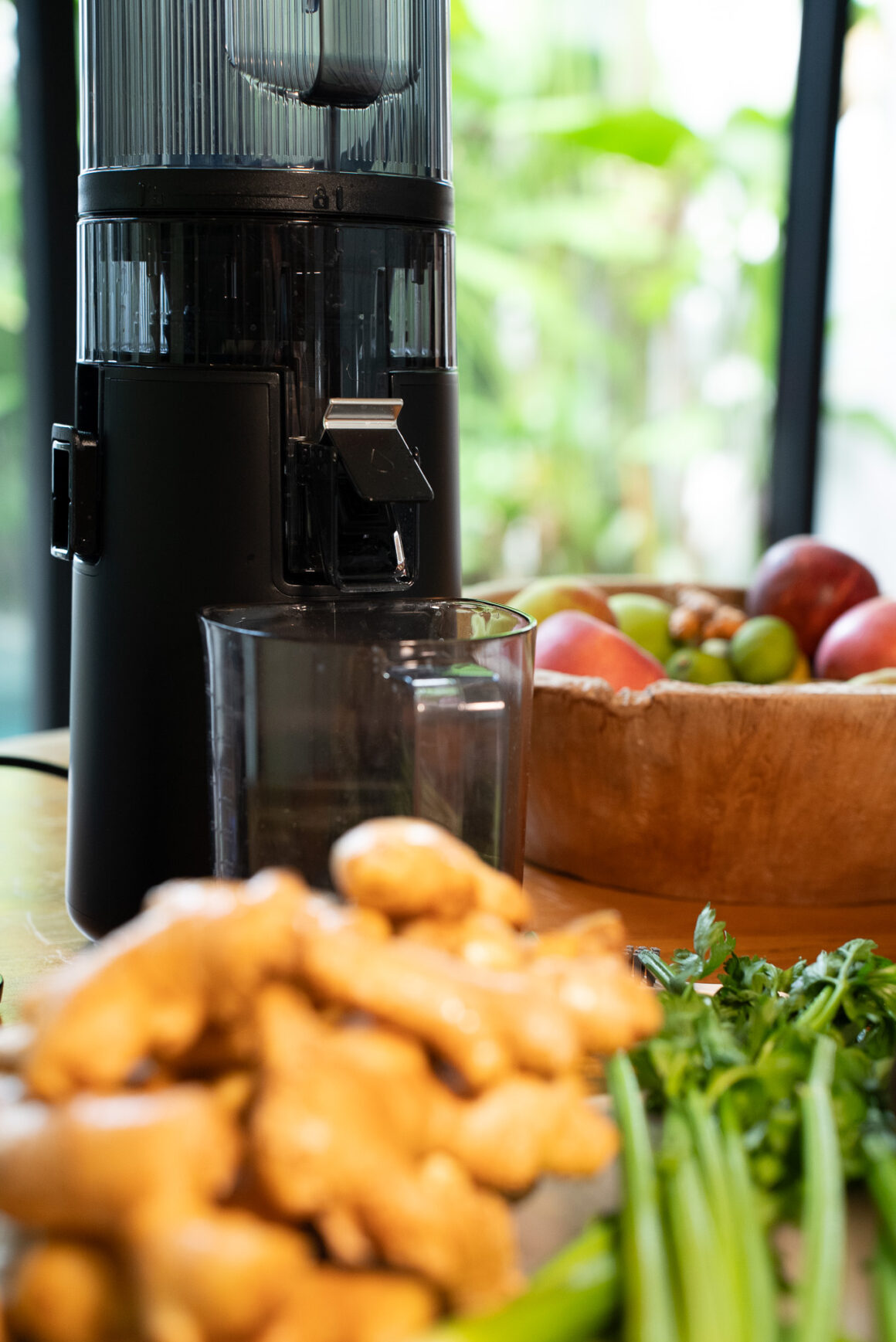 Hurom H70-ST Slow Juicer auf der Arbeitsplatte, Saftbehälter bereit – vertikales Design, moderne Küche im Hintergrund.