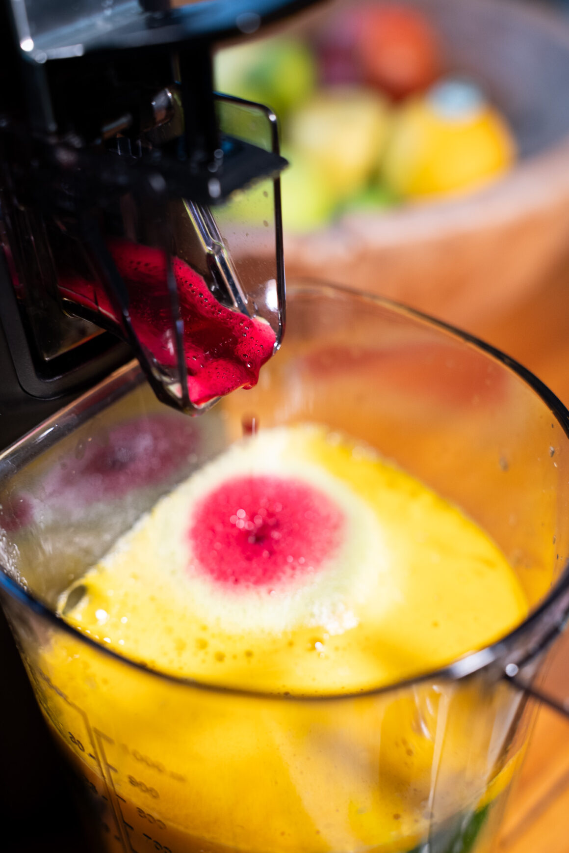 Rote-Bete-Saft fließt in gelben Saft aus dem Hurom H70-ST – intensiver Farbkontrast, präziser Auslauf.