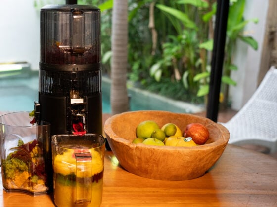 Hurom H70-ST auf Holztisch neben Obstschale – natürliche Küchenkulisse für veganes Cold-Press-Juicing.