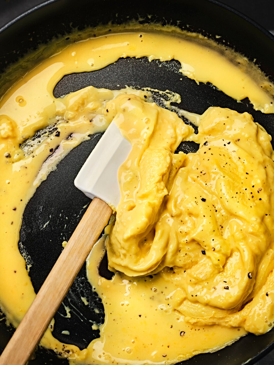 Pflanzliches Rührei aus JUST Egg stockt in der Pfanne und wird mit einem Spatel verrührt