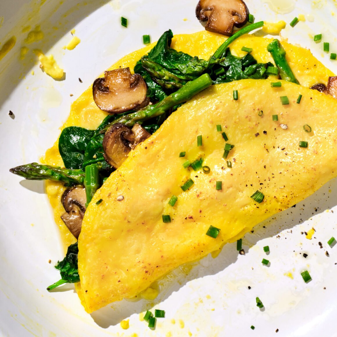 Veganes Omelett aus JUST Egg mit Spargel, Champignons und Spinat, bestreut mit Schnittlauch