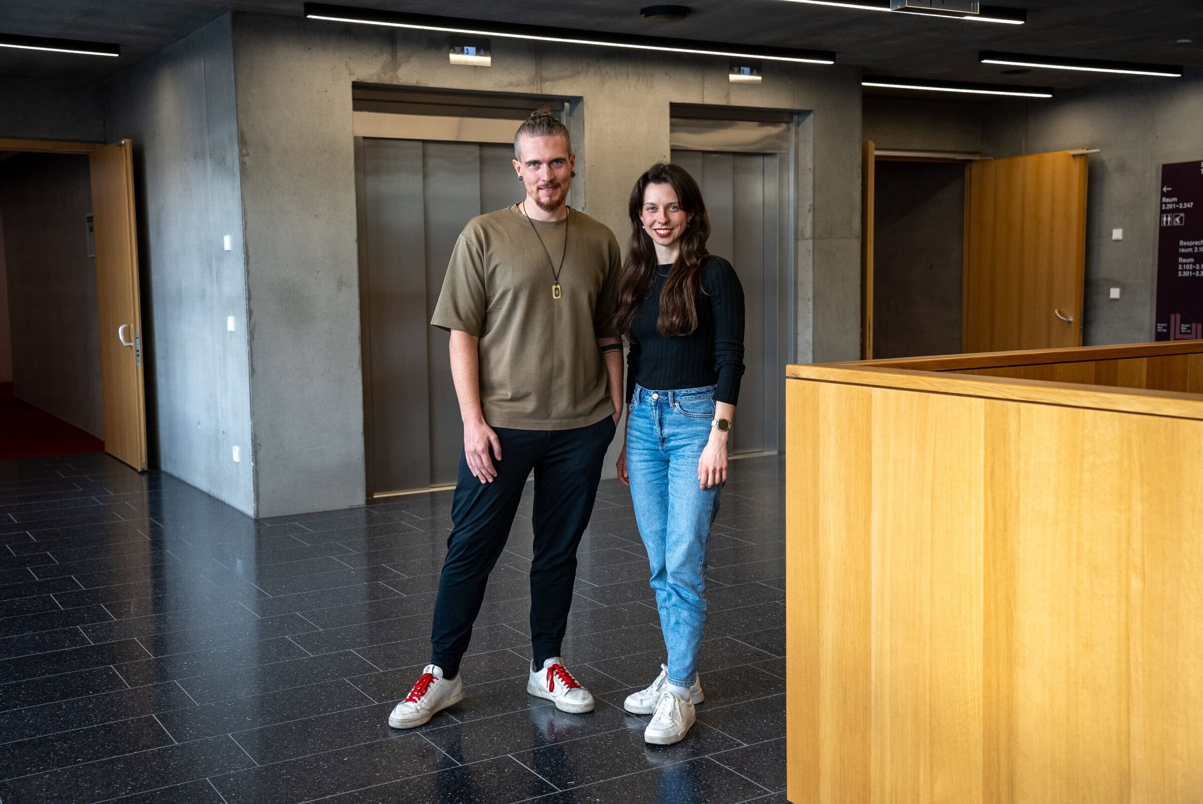 Dr. Zoe Mayer im Gespräch mit einem jungen Mann im modernen Gebäude.