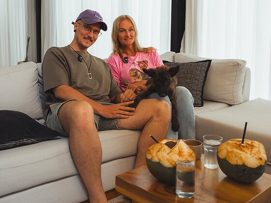 Femke Den Haas sitzt mit Hund auf Sofa, umgeben von veganen Snacks, bei Mission Bali für Tierschutz.
