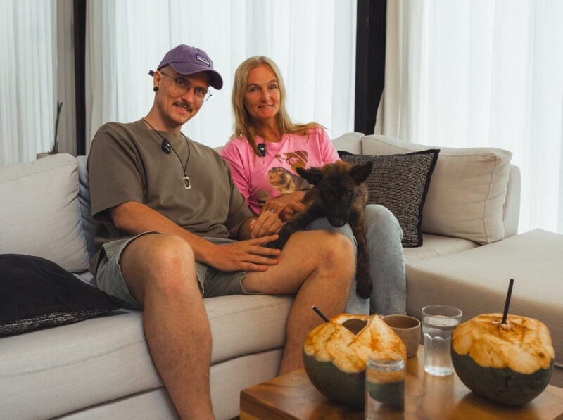 Femke Den Haas sitzt mit Hund auf Sofa, umgeben von veganen Snacks, bei Mission Bali für Tierschutz.