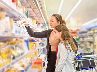 Mutter und Tochter kaufen veganen Käse im Supermarkt