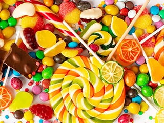 Vegane Süßigkeiten verschiedener Marken auf Holzbrett – Schokolade, Gummibärchen, Riegel und Bonbons