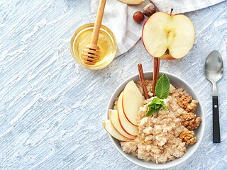 Schale mit Haferflocken, Walnüssen, veganem Honig, Leinsamen und Beeren auf Holztisch – Lebensmittel mit cholesterinsenkender Wirkung