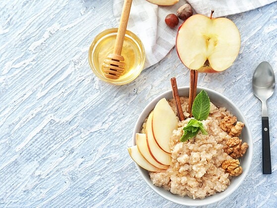 Schale mit Haferflocken, Walnüssen, veganem Honig, Leinsamen und Beeren auf Holztisch – Lebensmittel mit cholesterinsenkender Wirkung