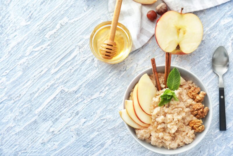 Schale mit Haferflocken, Walnüssen, veganem Honig, Leinsamen und Beeren auf Holztisch – Lebensmittel mit cholesterinsenkender Wirkung