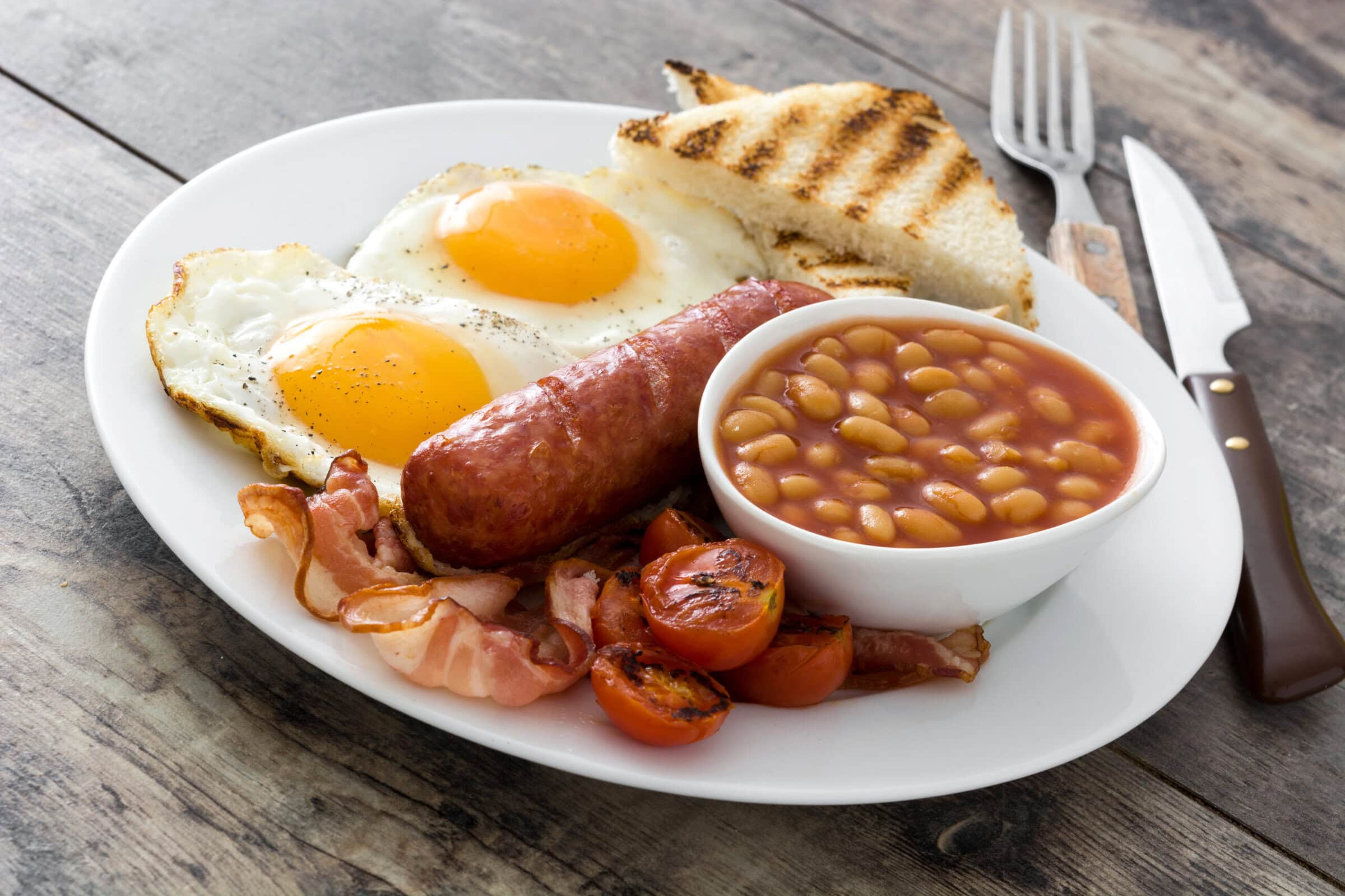 Klassisches Full English Breakfast mit Spiegelei, Wurst, Speck, Bohnen und getoastetem Brot