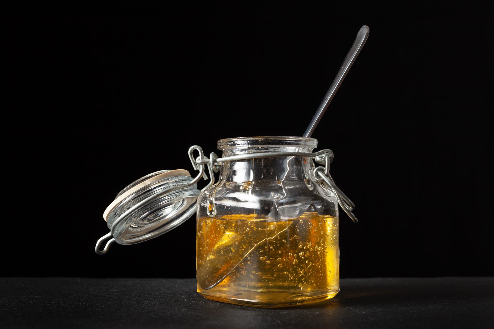 Goldener Agavendicksaft im Glas mit Holzlöffel, vegane Honig-Alternative für Tee und Backen