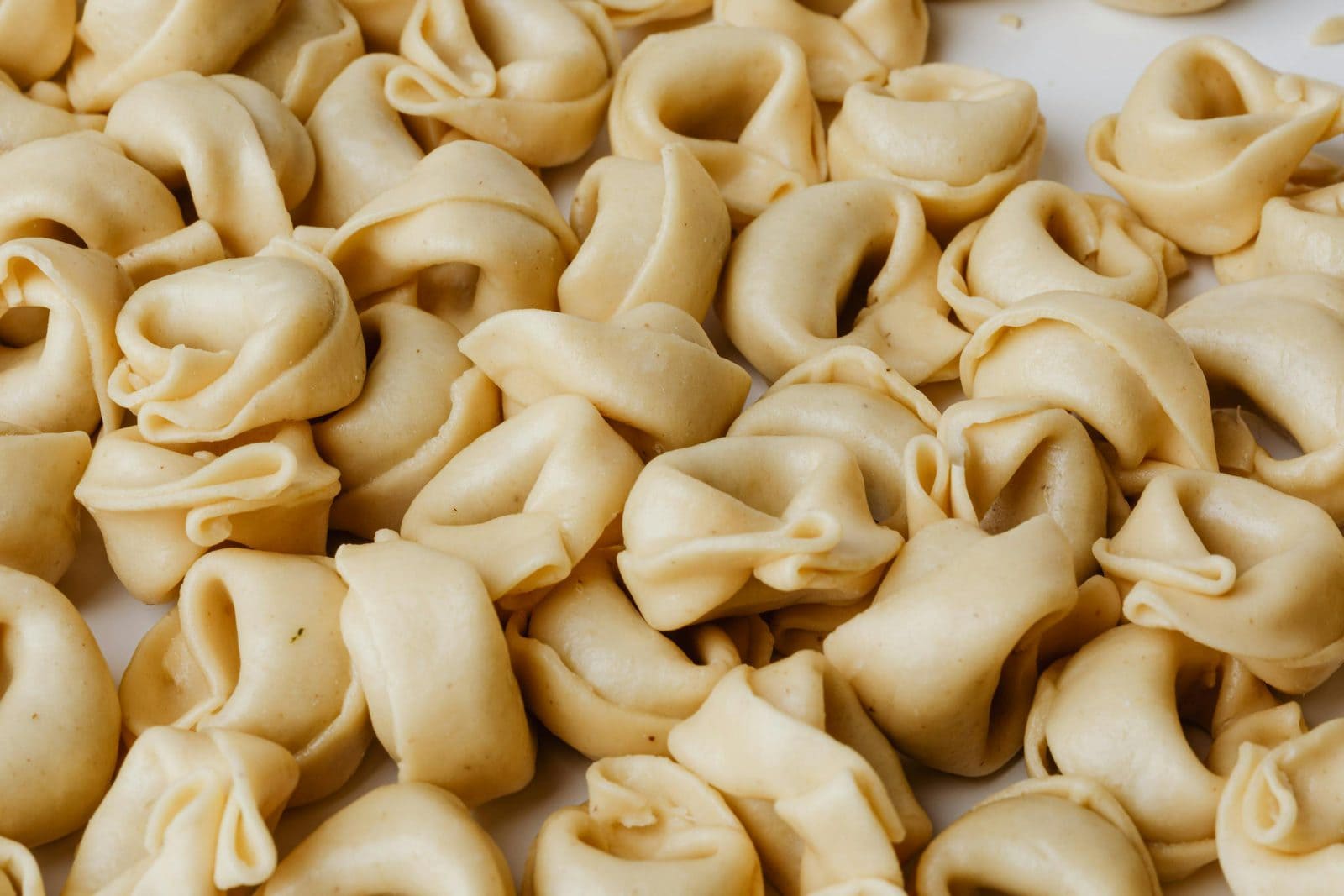 Hausgemachte Tortellini auf einem mit Mehl bestäubten Holzbrett, gefüllte Pasta-Variante