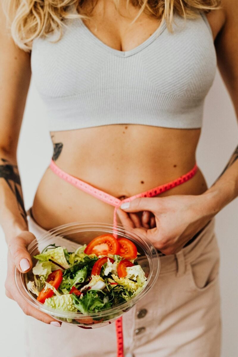 Frische Gemüseplatte mit Hülsenfrüchten, Quinoa und einer Personenwaage, helle Küche im Hintergrund