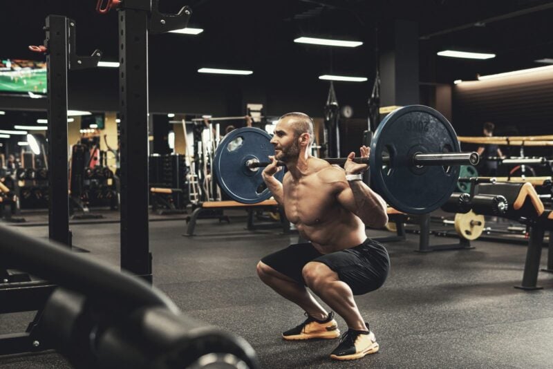 Sportler beim Krafttraining mit Hantel im Studio, fokussierter Muskelaufbau-Workout