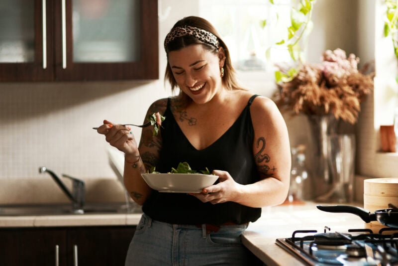 Frau isst gesunden veganen Salat in moderner Küche