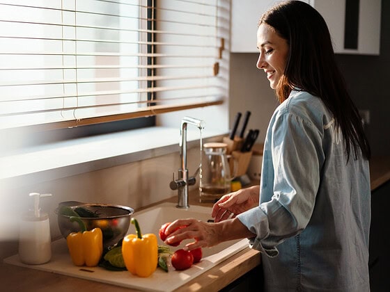 Frau wäscht frisches Gemüse für eine vegane Mahlzeit