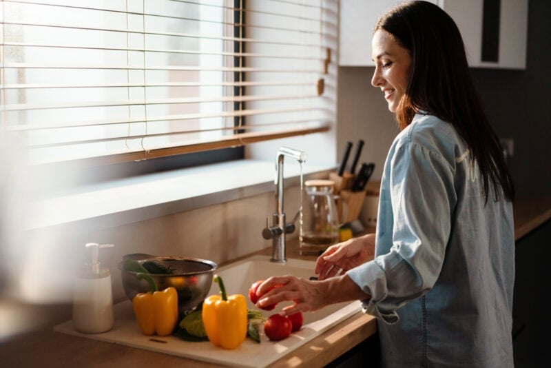Frau wäscht frisches Gemüse für eine vegane Mahlzeit