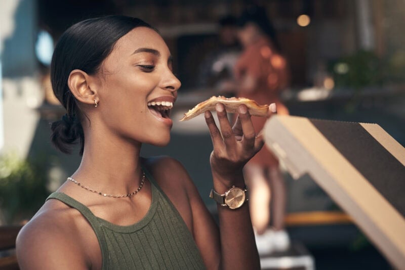 Junge Frau genießt eine vegane Pizza mit großem Appetit
