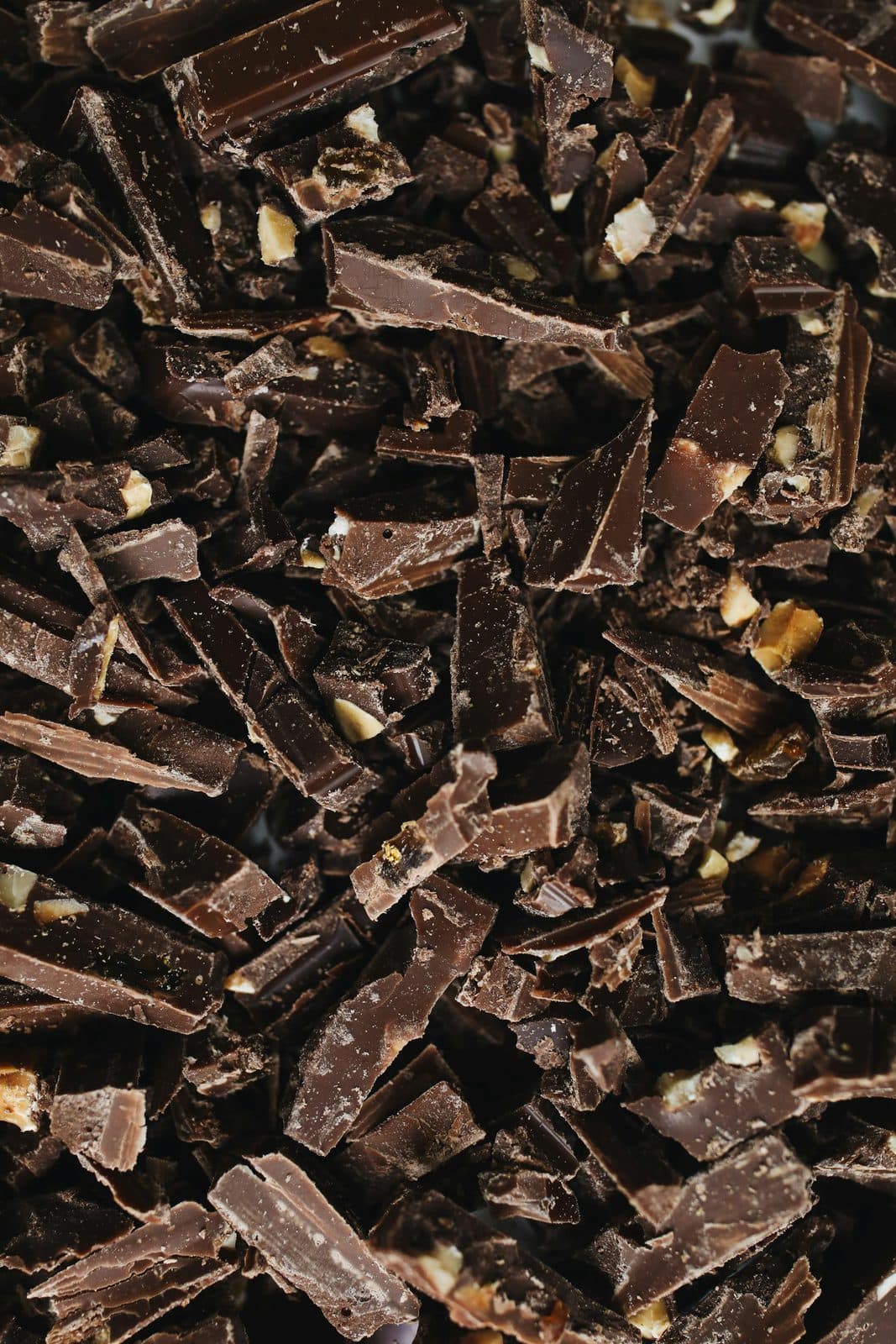 Dunkle Schokolade in Stücken auf Holzbrett, hochwertige Bitter-Tafel zum Brechen