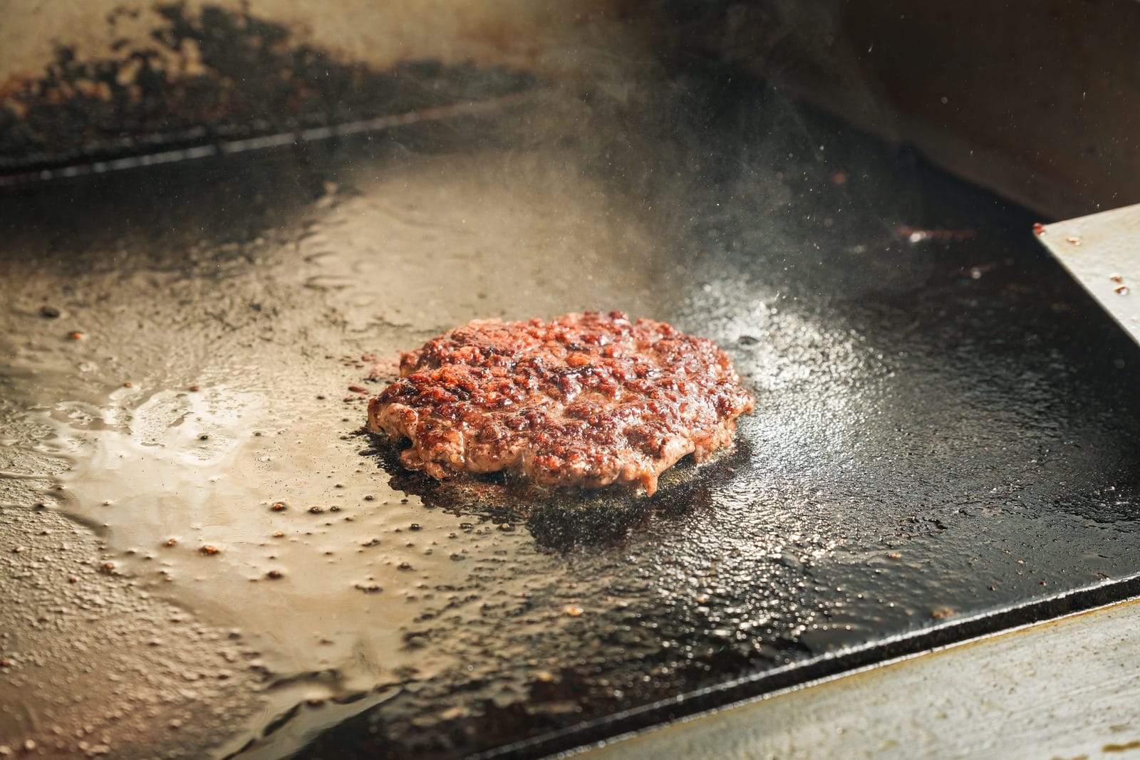 Veganer Burger-Patty in der Pfanne mit etwas Öl, goldbraun angebraten