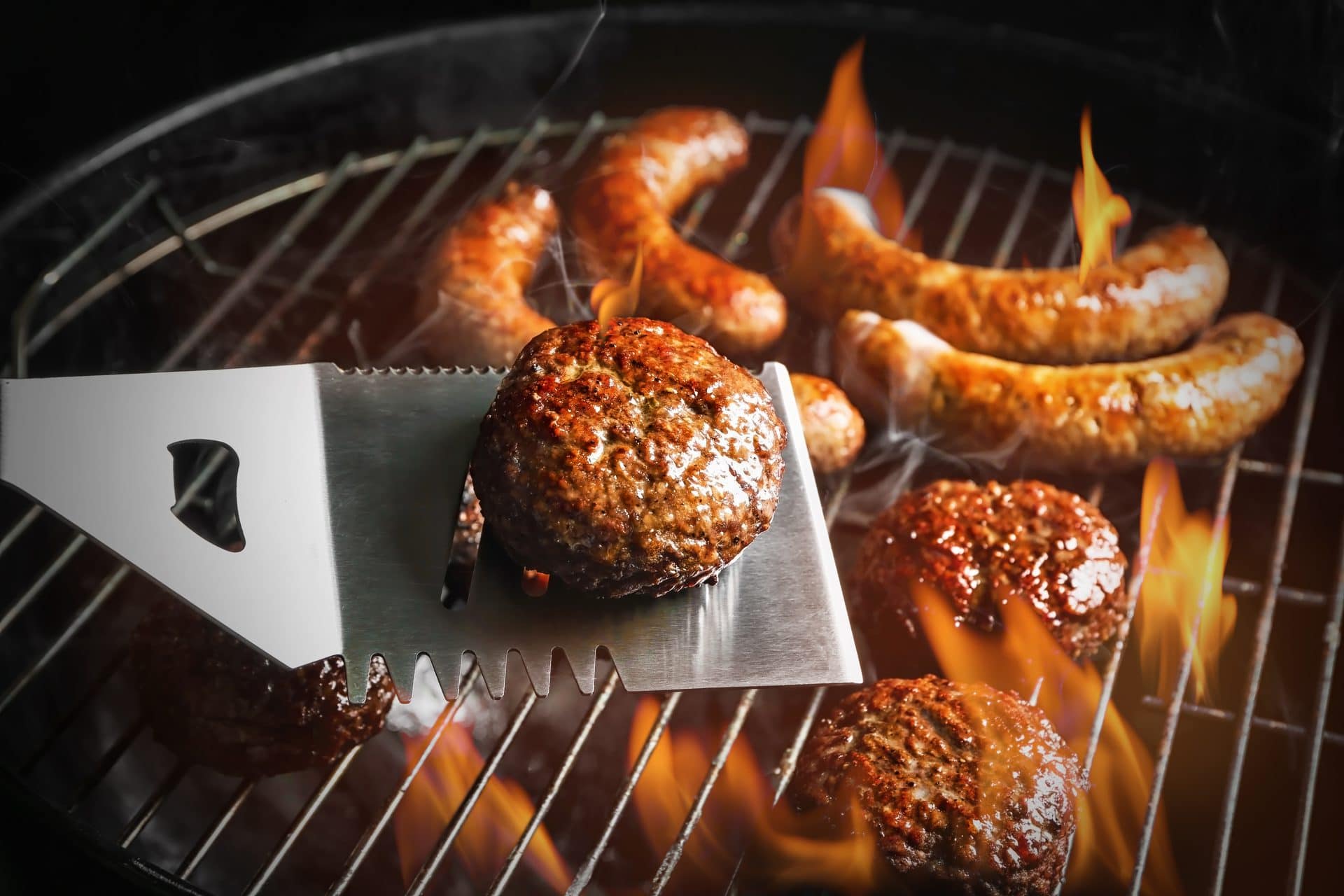 Vegane Burger-Pattys und Würste auf einem Grill mit Flammen