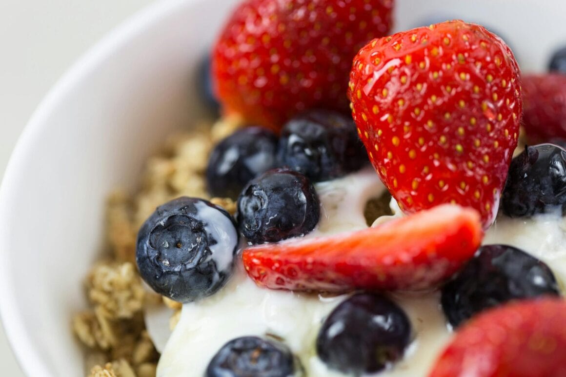 Verschiedene vegane Joghurts in Gläsern und Bechern mit Beeren, Haferflocken und Honig-Alternative