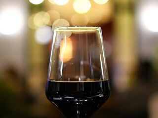 Glas Rotwein vor unscharfen Lichtern