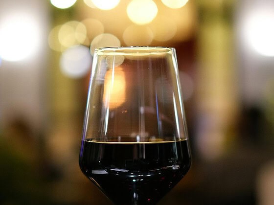 Glas Rotwein vor unscharfen Lichtern