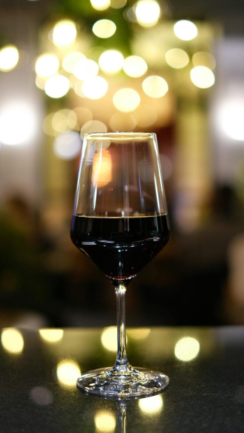 Glas Rotwein vor unscharfen Lichtern