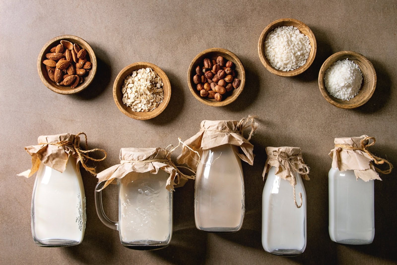 Pflanzliche Milch-Sorten in Glasflaschen: Mandel, Haselnuss, Kokos, Reis, Hafer