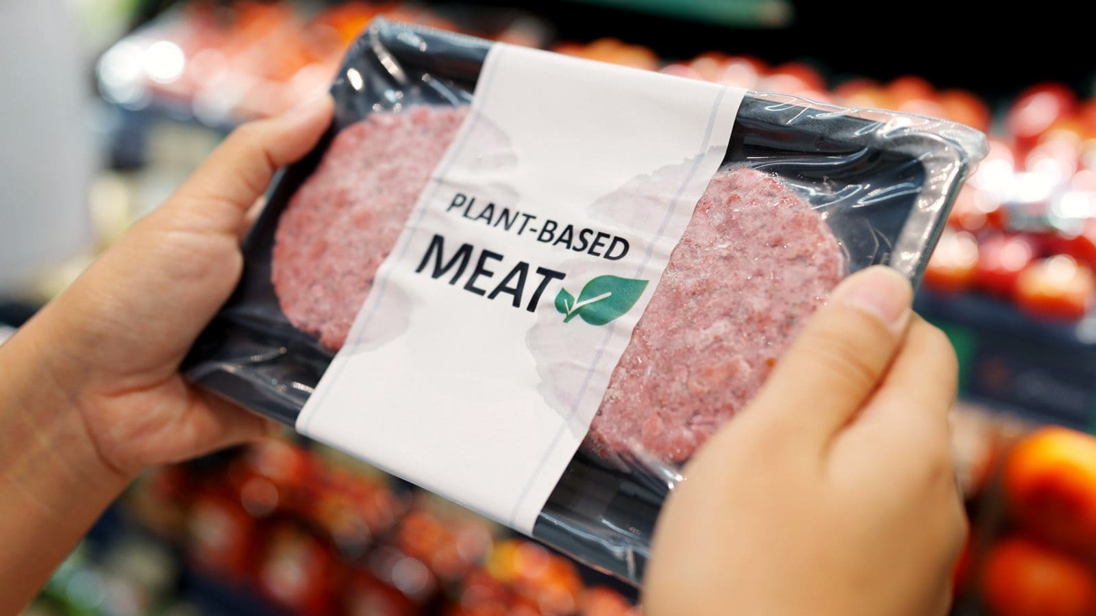 Hände halten eine Verpackung mit Plant-based-Label im Supermarkt und prüfen die Kennzeichnung