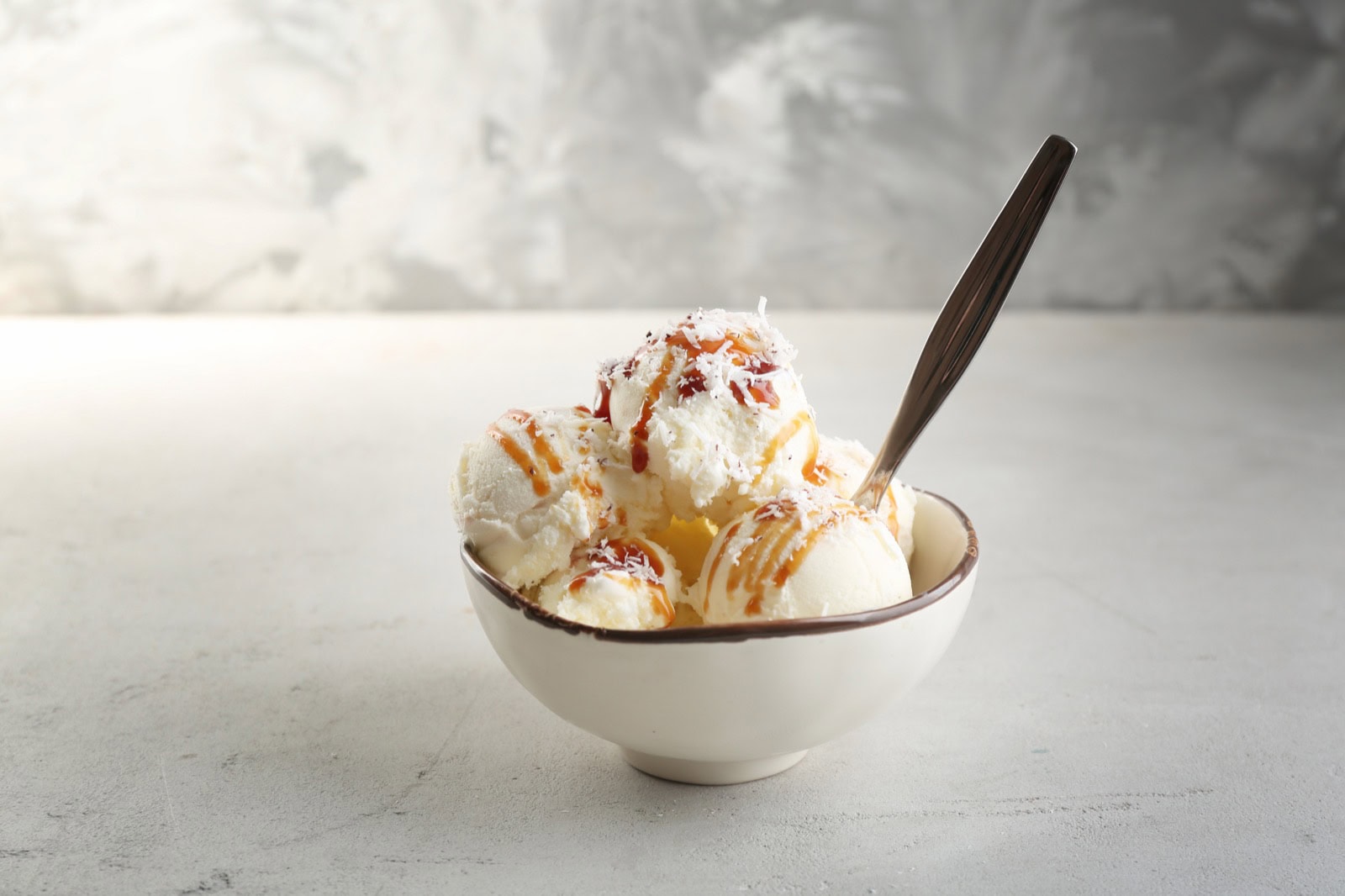Schale mit Kokos-Eis-Kugeln und Karamell-Sirup