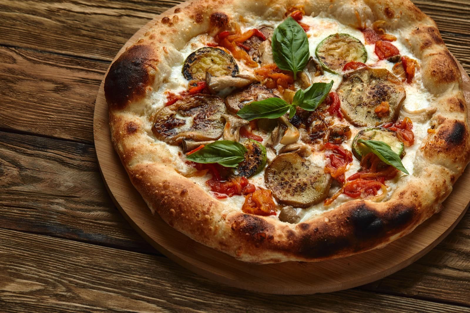 Vegane Pizza mit verschiedenen Gemüse-Belägen auf weißem Hintergrund