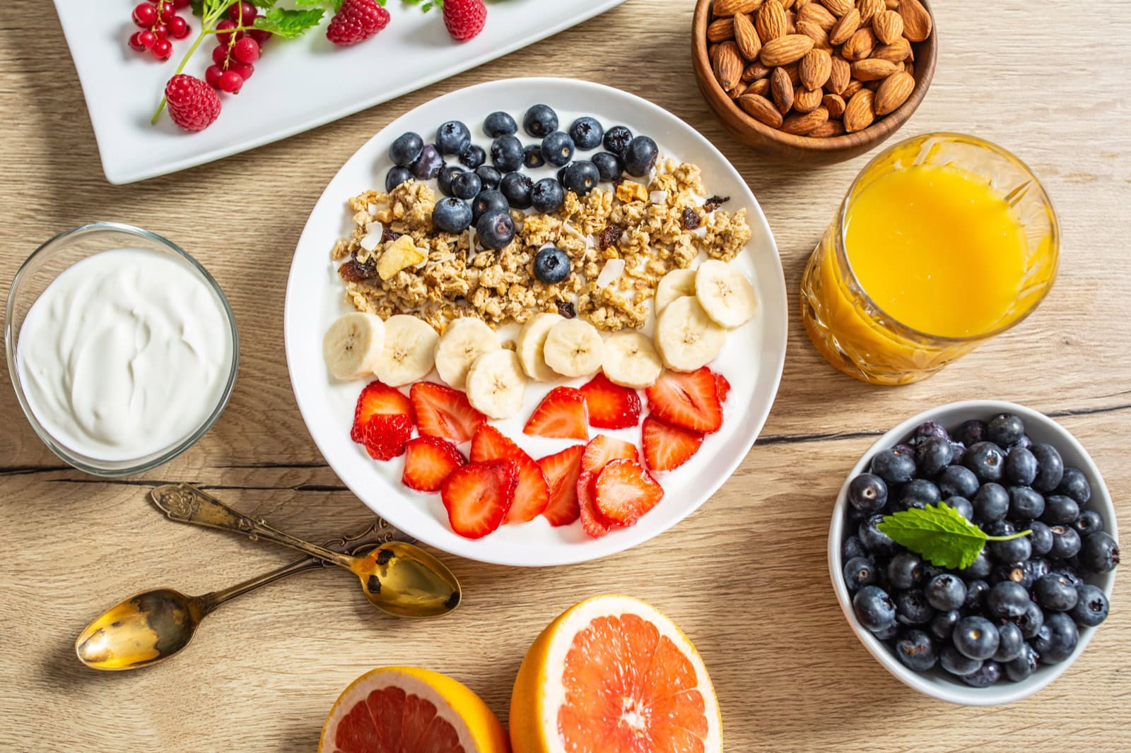 Veganer Joghurt mit Müsli, Heidelbeeren, Erdbeeren und Banane auf weißem Teller