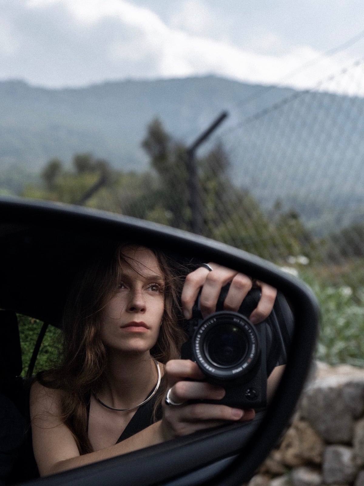 Aglaja Brix als Fotografin mit Kamera im Rückspiegel eines Autos
