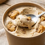 Ben & Jerry's vegan: Diese Sorten sind es Geöffneter veganer Eisbecher mit Löffel, cremiges Eis mit Cookie-Stücken